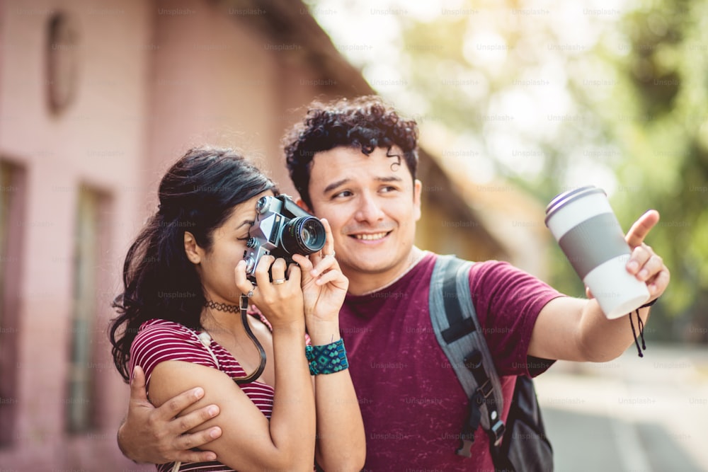 Young couple standing on street. Girl uses a camera.