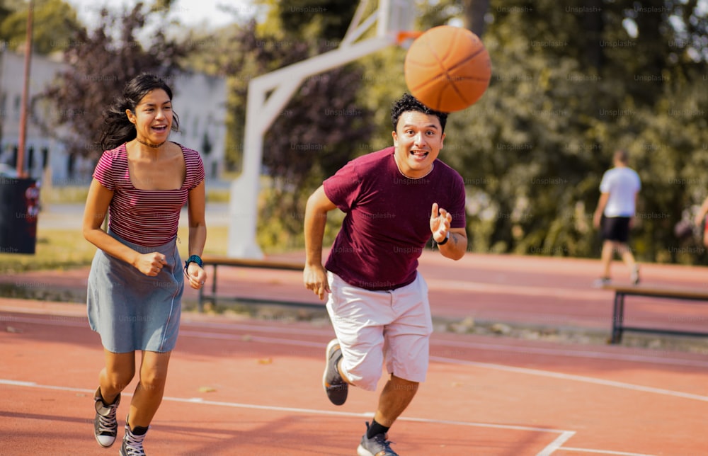 Young couple playing basketball. Focus is on woman and man.
