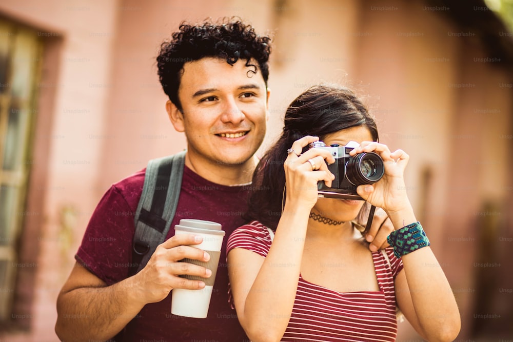 Young couple standing on street. Girl uses a camera.