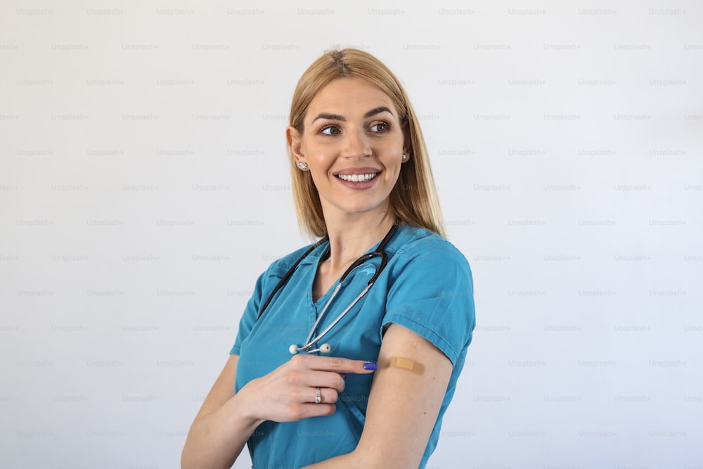 Ritratto di una dottoressa che sorride dopo aver ricevuto un vaccino. Operatore sanitario che mostra il braccio con la benda dopo aver ricevuto la vaccinazione.