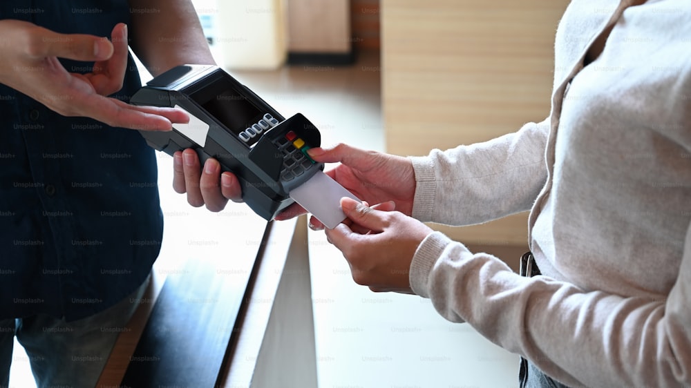 Weibliche Zahlung mit einer Kreditkarte über das Terminal.