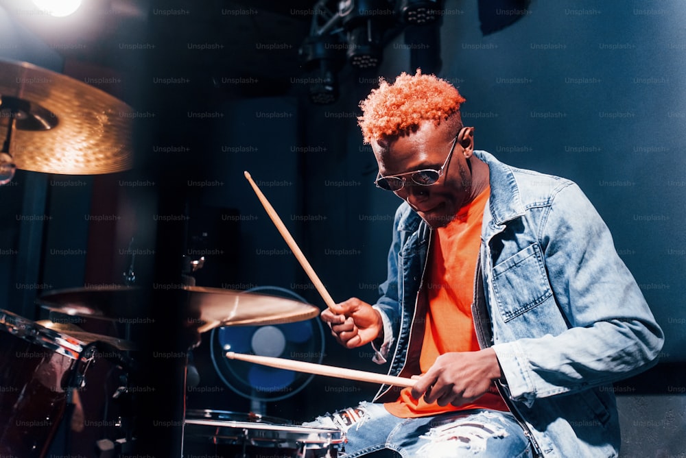 Spielt Schlagzeug. Junger afroamerikanischer Performer probt in einem Tonstudio.