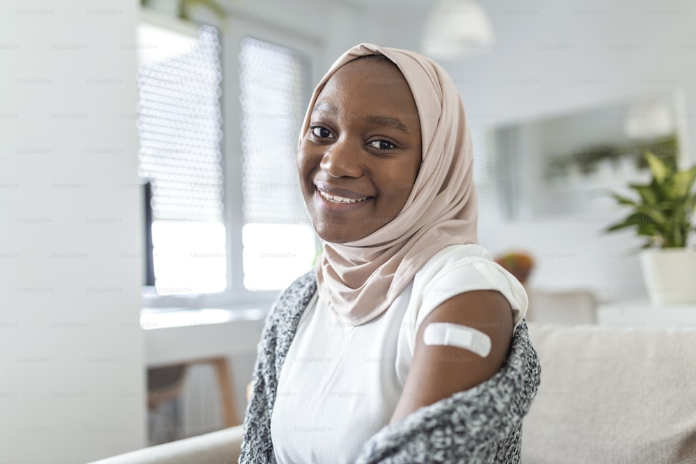 Vendaje adhesivo en el brazo después de la inyección, vacuna o medicamento,VENDAJES ADHESIVOS YESO - Equipo médico,Enfoque suave Vendaje adhesivo en una mujer africana musulmana braquio después de la vacunación covid-19