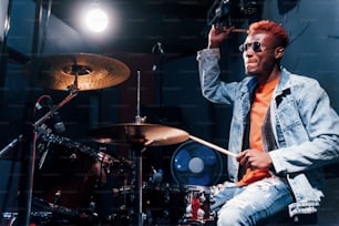 Plays drums. Young african american performer rehearsing in a recording studio.