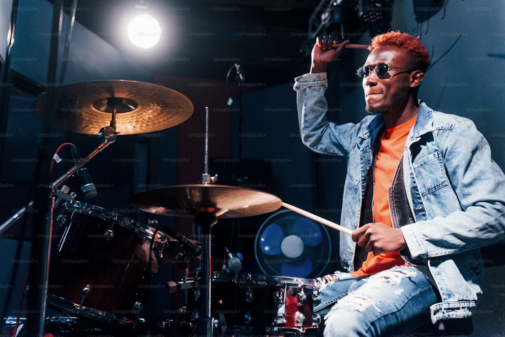 Plays drums. Young african american performer rehearsing in a recording studio.