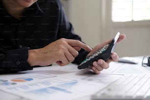 Concept de comptabilité d’entreprise, homme d’affaires utilisant une calculatrice avec un ordinateur portable, un budget et un papier de prêt au bureau.