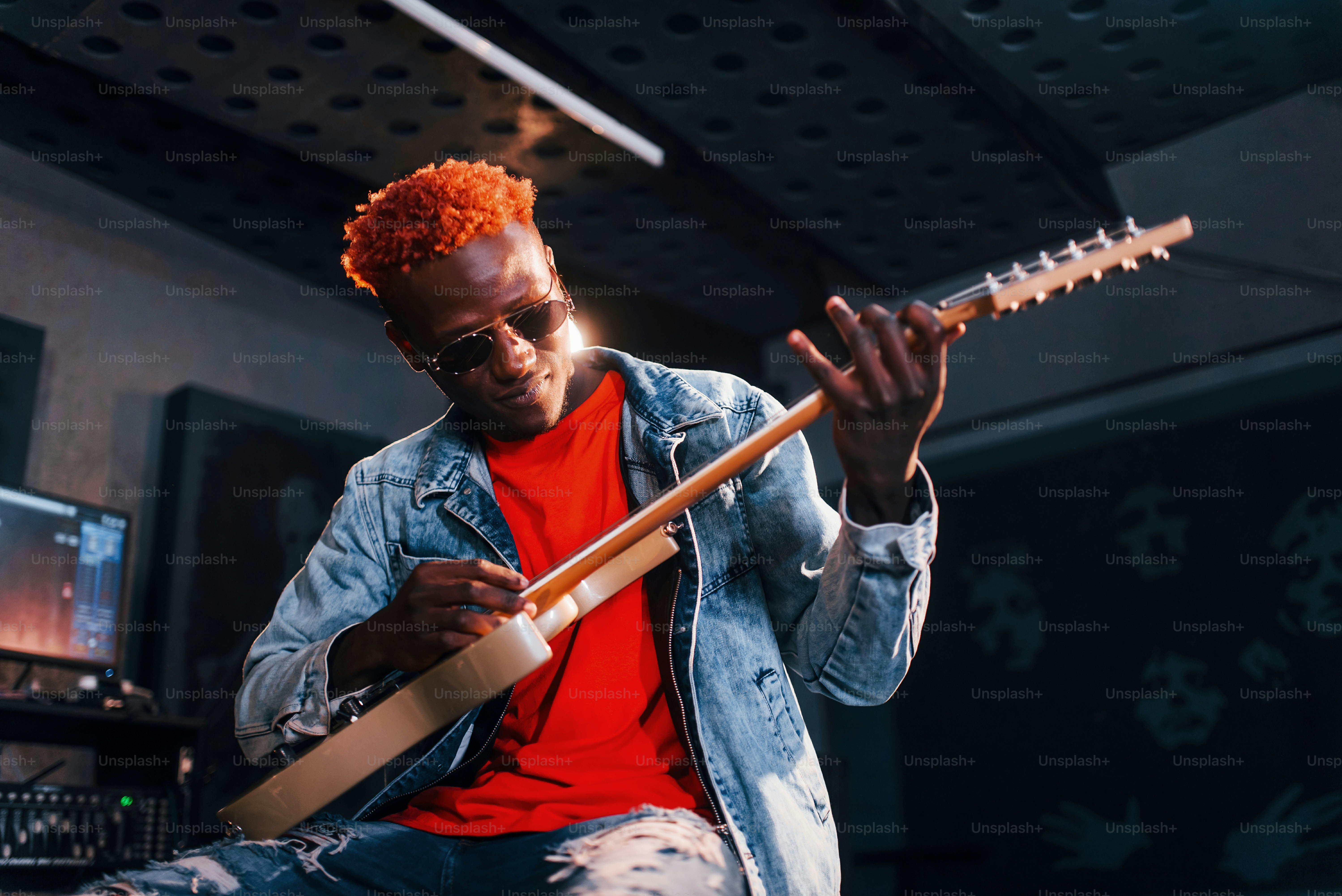 Bermain gitar. Penampil muda Afrika-Amerika berlatih di studio rekaman