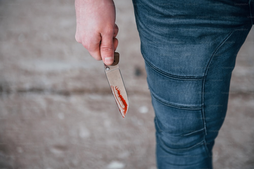 Close up view of killer that standing with knive with blood in hand.