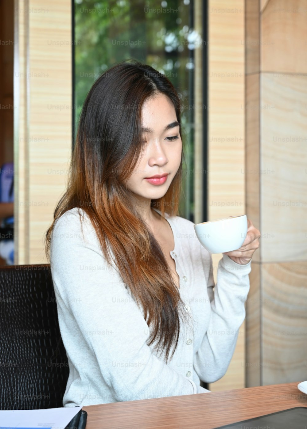 Giovane donna che beve caffè in un ufficio moderno.