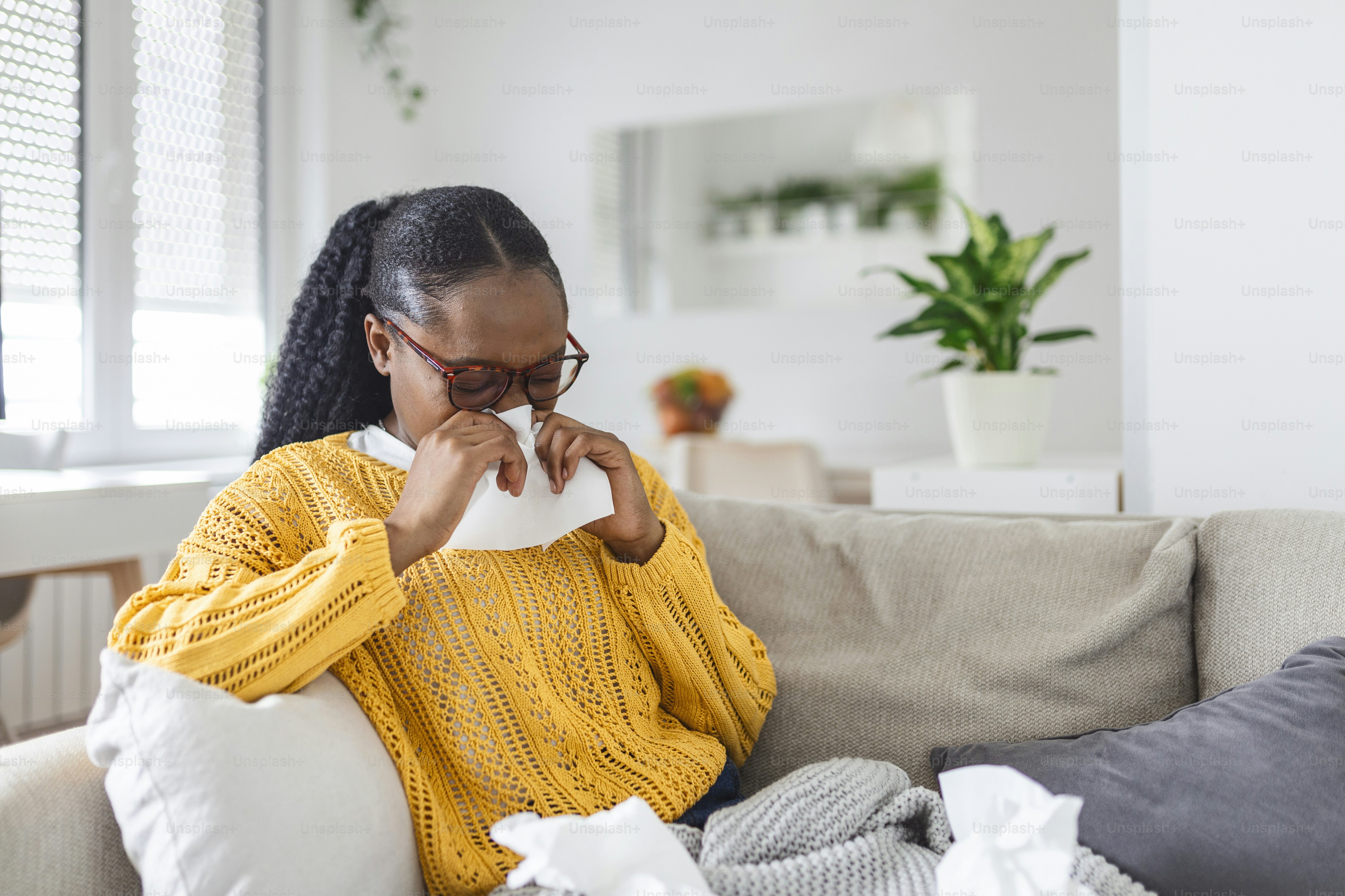 Sick day at home. Young woman has runny and common cold. Cough. Closeup Of Beautiful Young Woman Caught Cold Or Flu Illness. Portrait Of Unhealthy woman with coronavirus, covid19 symptoms