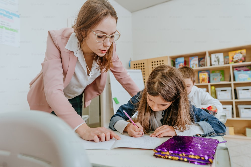 Female teacher helping schoolgirl in the classroom. Back at school concept. Selective focus.