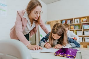 Female teacher helping schoolgirl in the classroom. Back at school concept. Selective focus.