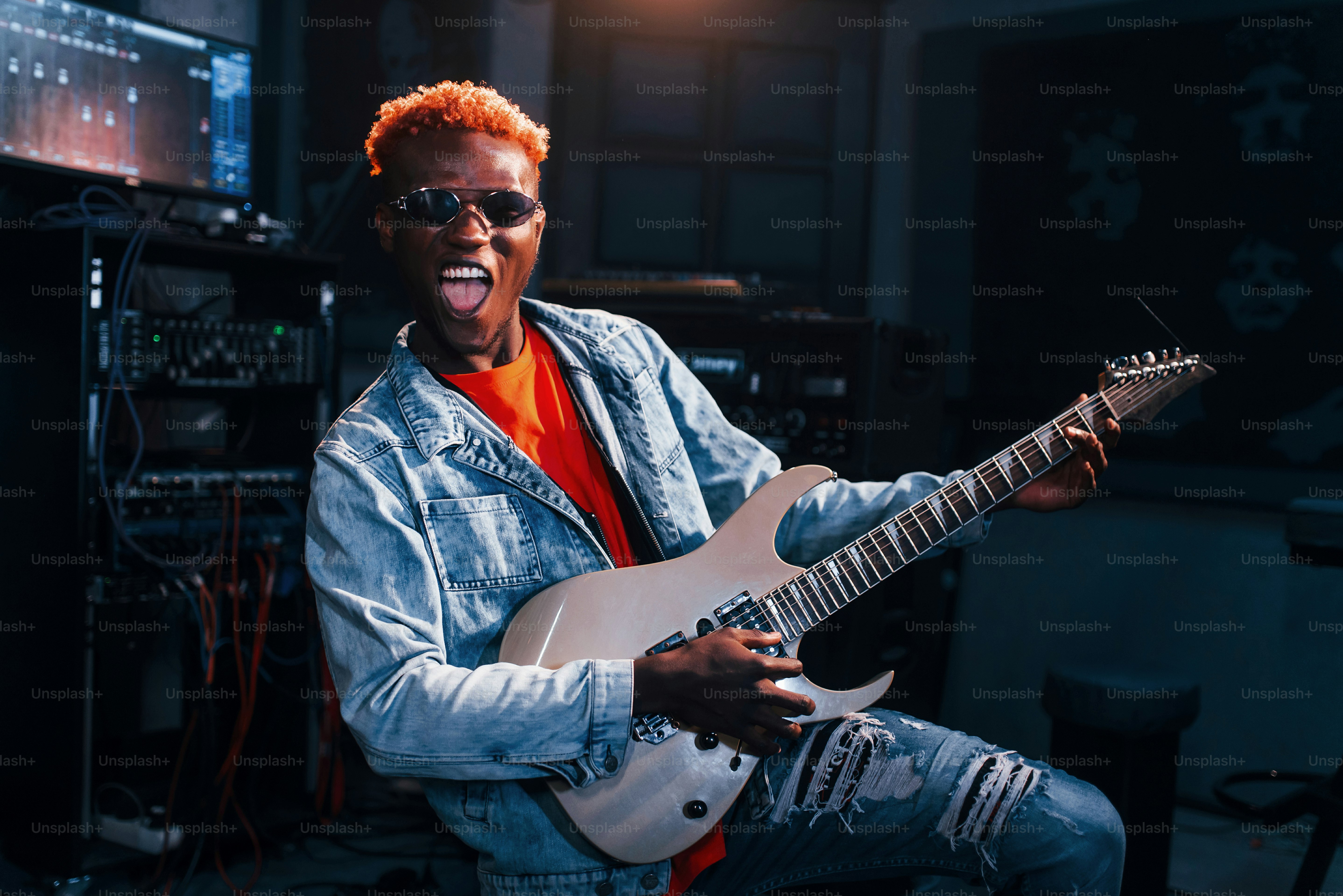 Bermain gitar. Penampil muda Afrika-Amerika berlatih di studio rekaman