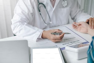 Close-up of a doctor examining the patient's pulse in the doctor office Medical device documents placed on the table.