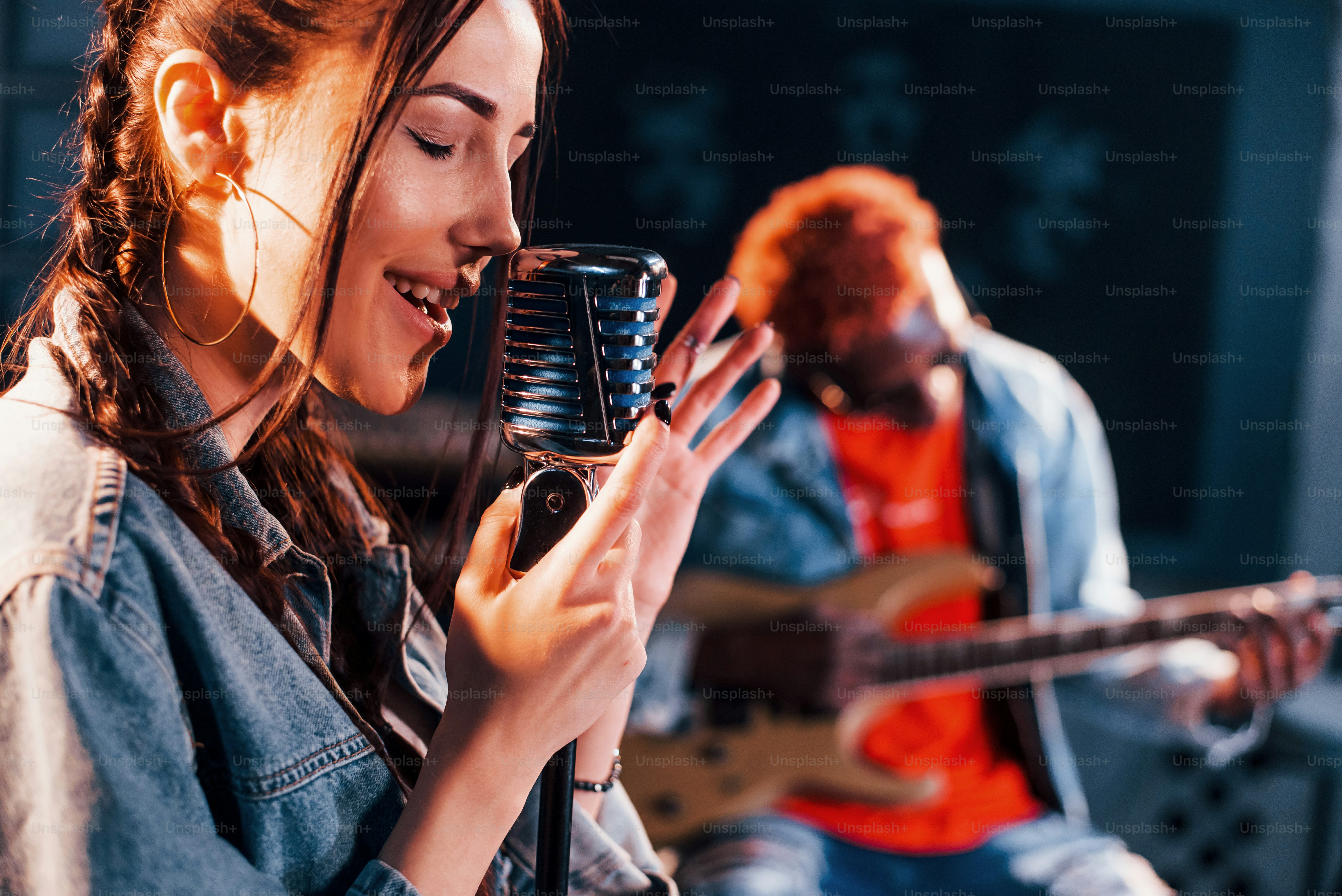 Guy plays guitar, girl sings. African american man with white girl rehearsing in the studio together.