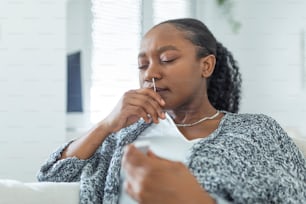 집에서 코로나바이러스 PCR 검사를 하는 동안 면봉을 사용하는 아프리카계 미국인 여성. 코로나바이러스 신속 진단 테스트를 사용하는 여성. COVID-19에 대해 비강 면봉을 사용하는 집에서 젊은 여성.