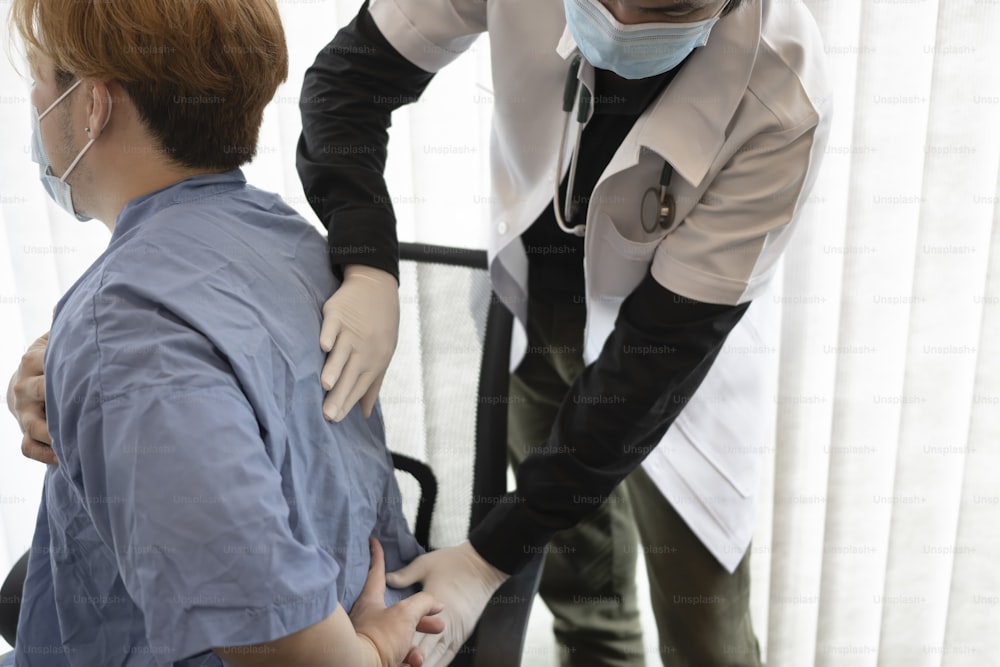 Médico examinando a un paciente que sufre de dolor de espalda.