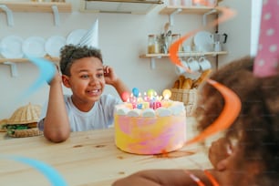 Happy sister and brother having fun time during birthday party in the kitchen. Selective focus on the boy's face.