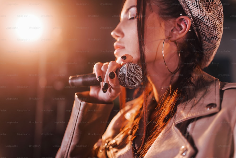 Young beautiful female performer rehearsing in a recording studio.