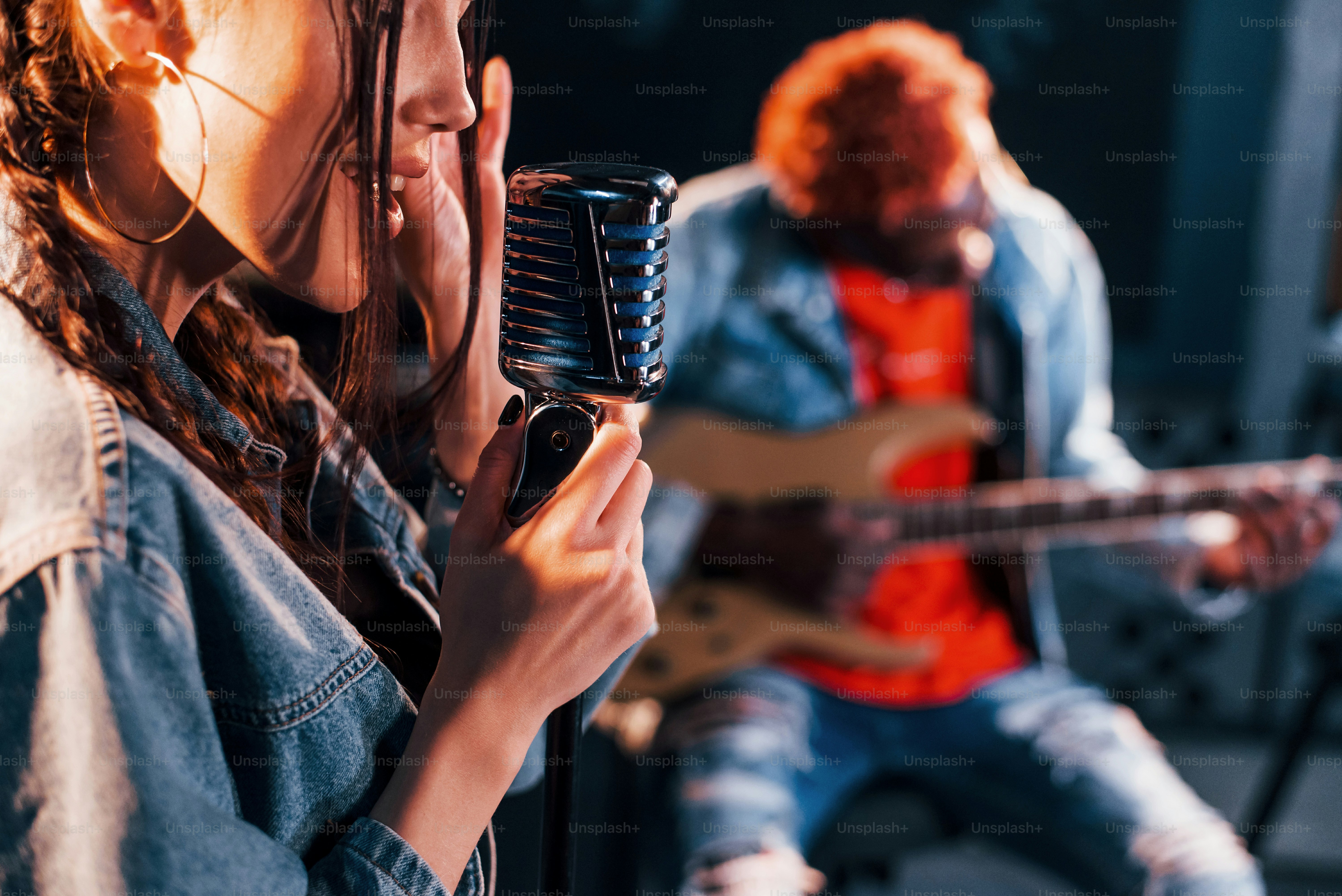 Guy plays guitar, girl sings. African american man with white girl rehearsing in the studio together.
