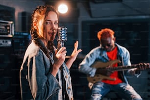 Guy plays guitar, girl sings. African american man with white girl rehearsing in the studio together.