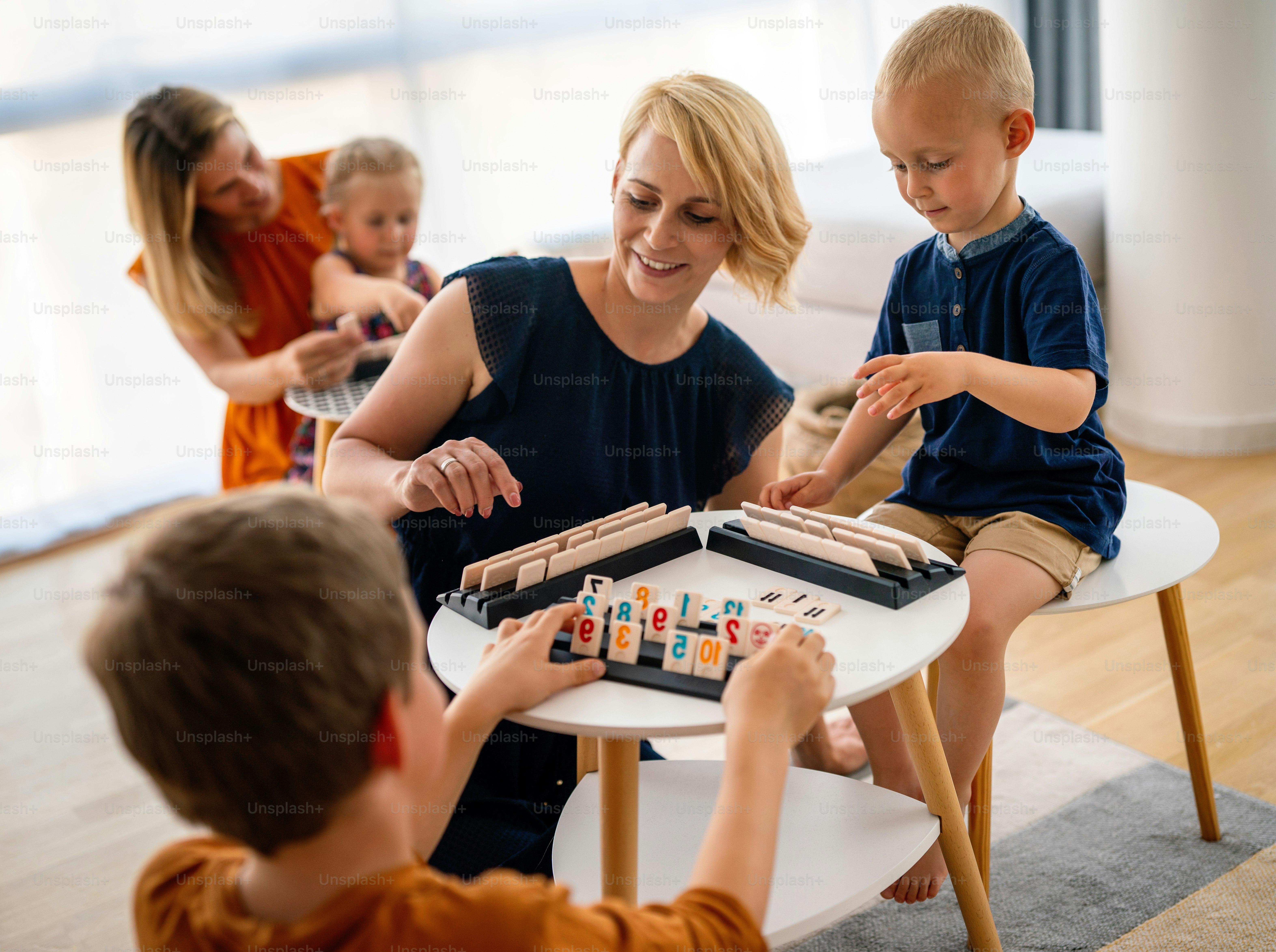 Young women at the table playing board game with children. Family, nursery, childhood concept.