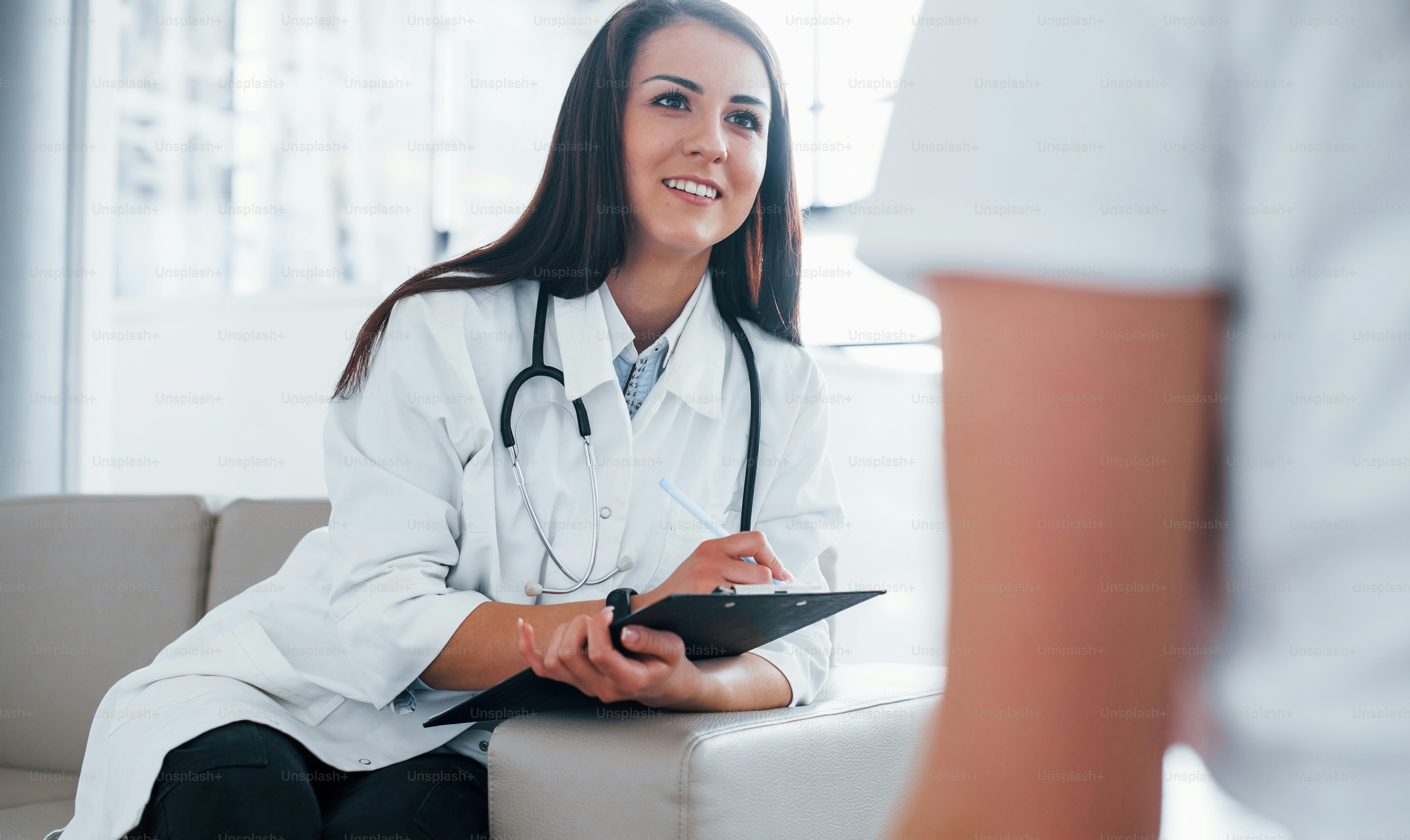 Friendly doctor listening to the patient. Young woman have a visit with female doctor in modern clinic.