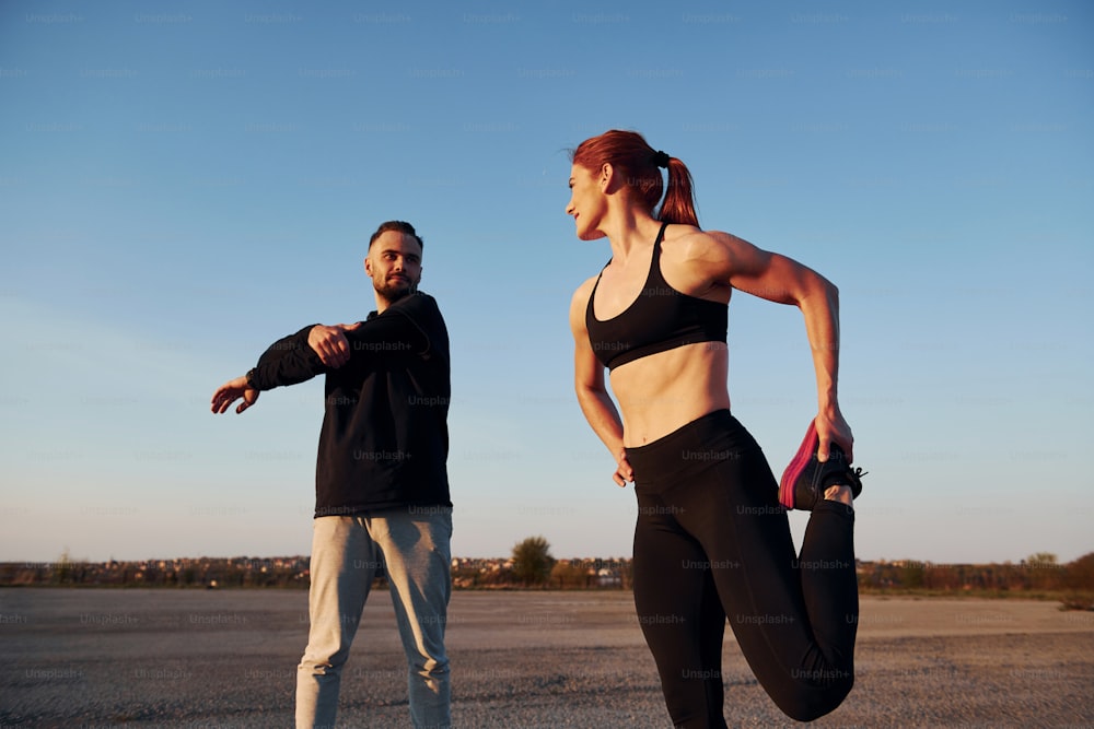 Woman and man have fitness day on the road at evening together.