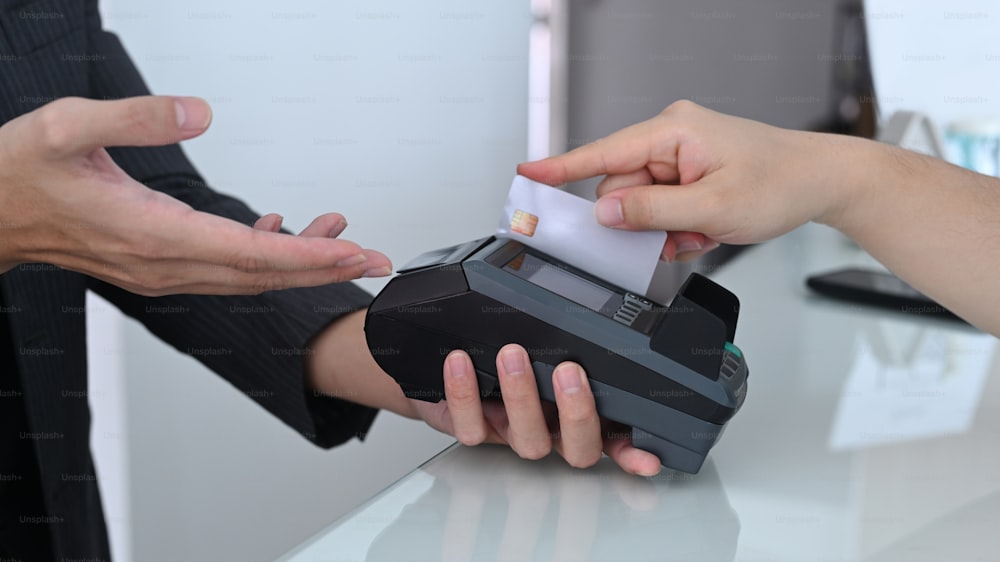 Woman swiping credit card through payment terminal.