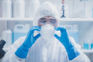医学の実験室、ウイルス病の流行インフルエンザ、診療所または病院での健康安全衛生のための保護服で働くための手袋とマスクを身に着けている科学者または医師