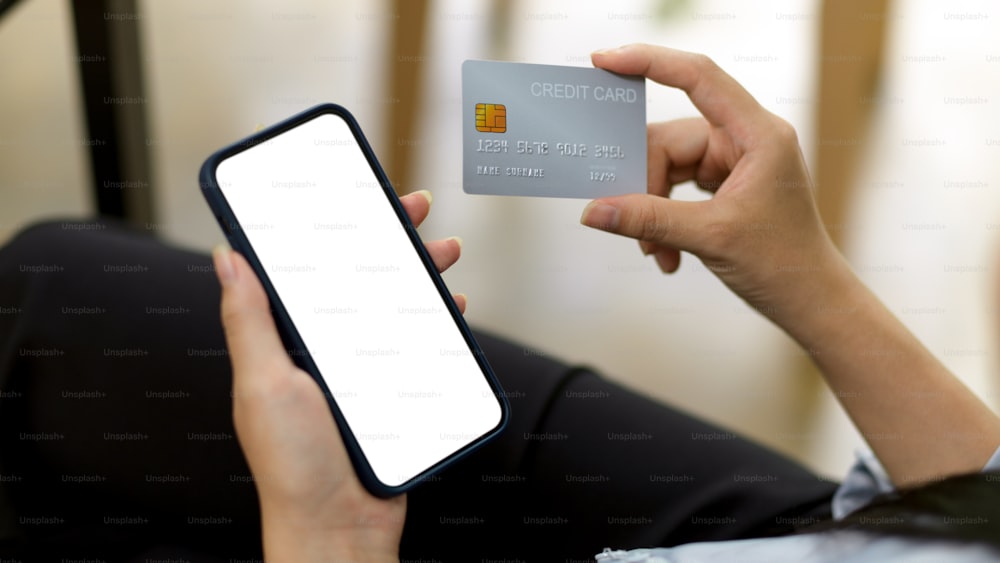 Mujer sostiene el teléfono inteligente en la pantalla en blanco y una tarjeta de crédito, maqueta de teléfono negro, dispositivo de tenencia, banca en línea, pago, aplicación