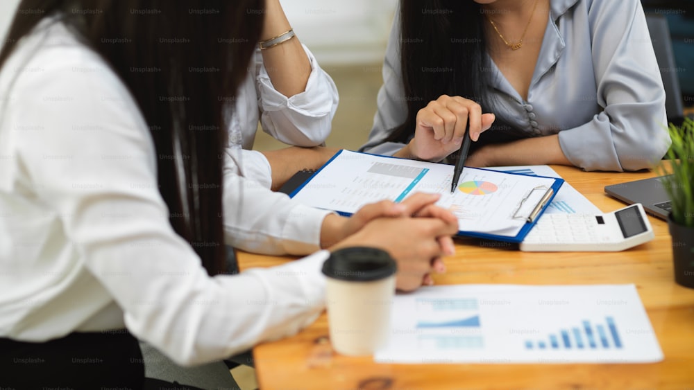 Crop shot of finance private tutor teaching college student with financial reports at cafe co-working space