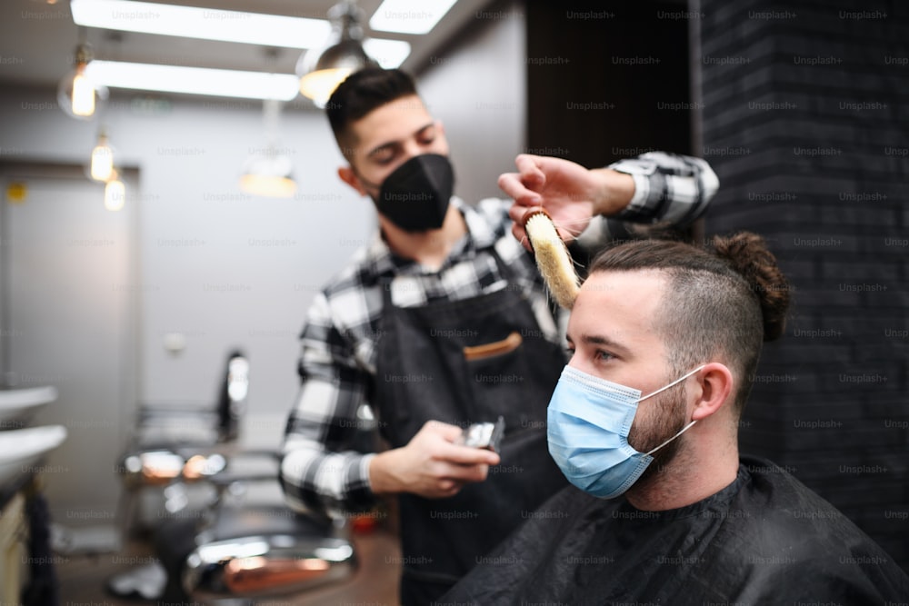 Cliente uomo in visita al parrucchiere e al parrucchiere nel negozio di barbiere, coronavirus e concetto di nuova normalità.