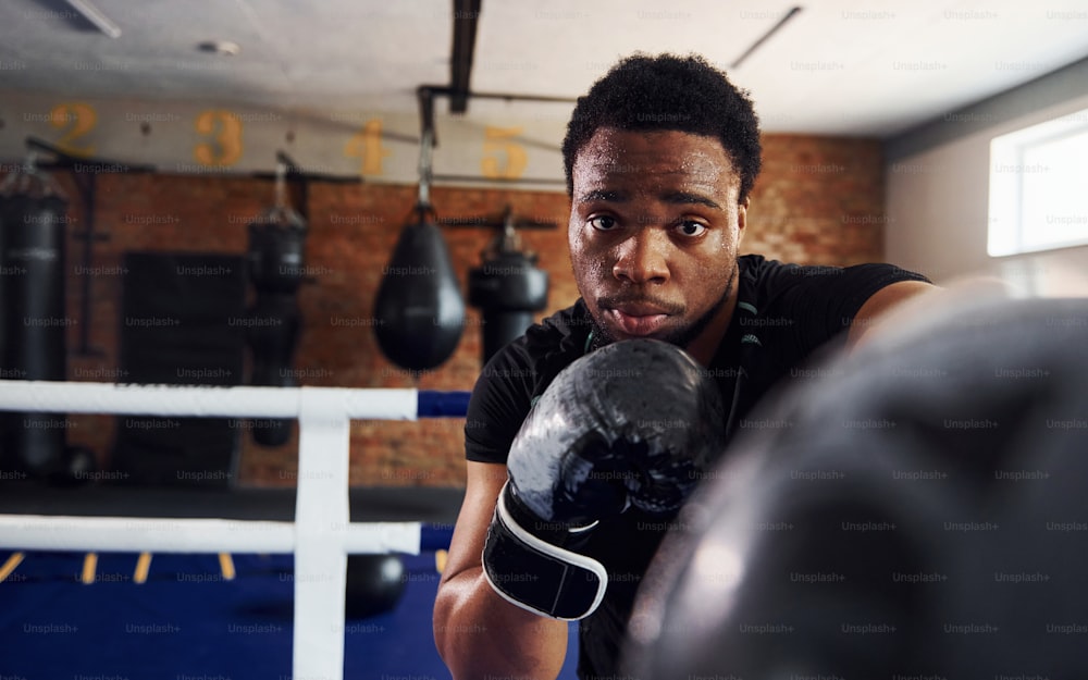 Strong african american boxer in sportive clothes have practice in the gym.