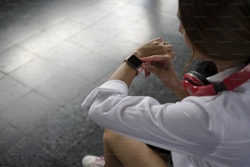 Young woman traveler checking time on her wristwatch at rail station platform.