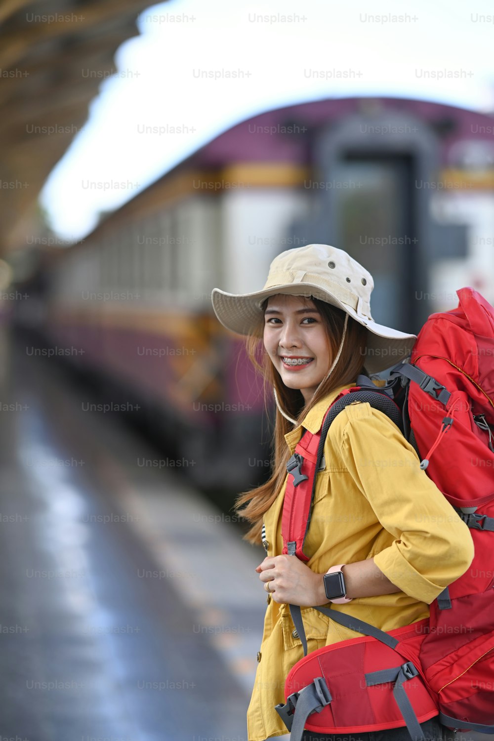 Portrait woman traveler standing at the train station and smiling to camera. Travel concept.