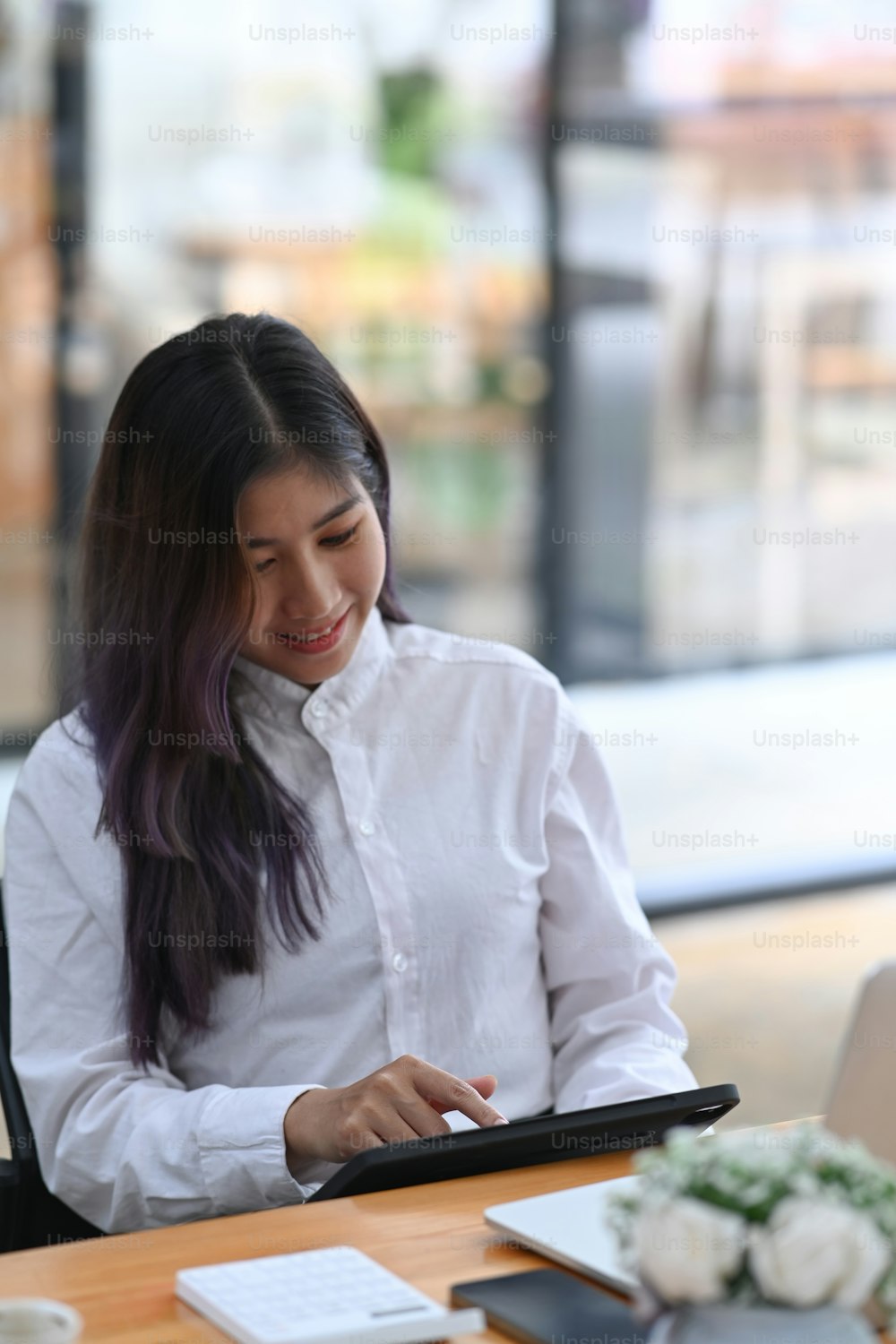 Employée de bureau heureuse assise à son bureau et utilisant une tablette numérique.
