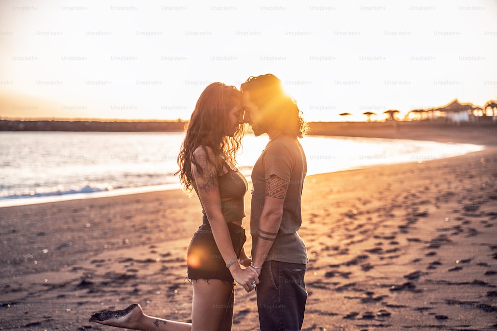 해변에서 아름 다운 사랑 스러운 젊은 커플, 손을 잡고. 실제 사람들의 감정. 사랑. 생활방식. 해질녘. 여름 섬 분위기.