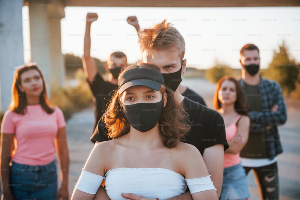 抱き合うカップル。一緒に立ち上がる抗議する若者のグループ。人権活動家、または政府に反対する活動家。