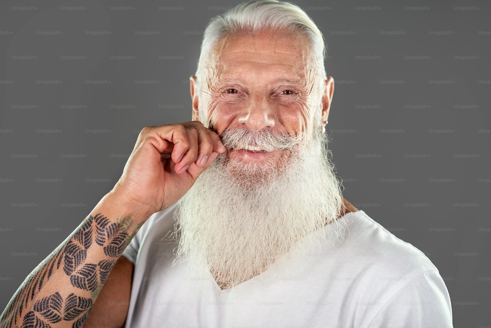웃고 있는 행복한 성숙한 수염 난 남자가 카메라를 보고 있다. 잘 생긴 자신감 있는 노인 남성의 초상화.