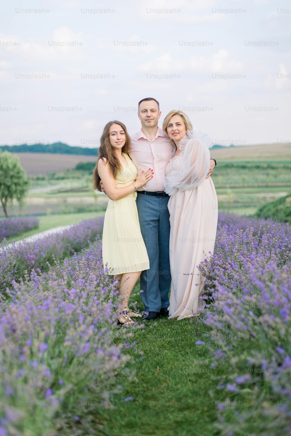 Happy family, handsome mature man, stunning lady and pretty pleasant young girl daughter, posing together in lavender field