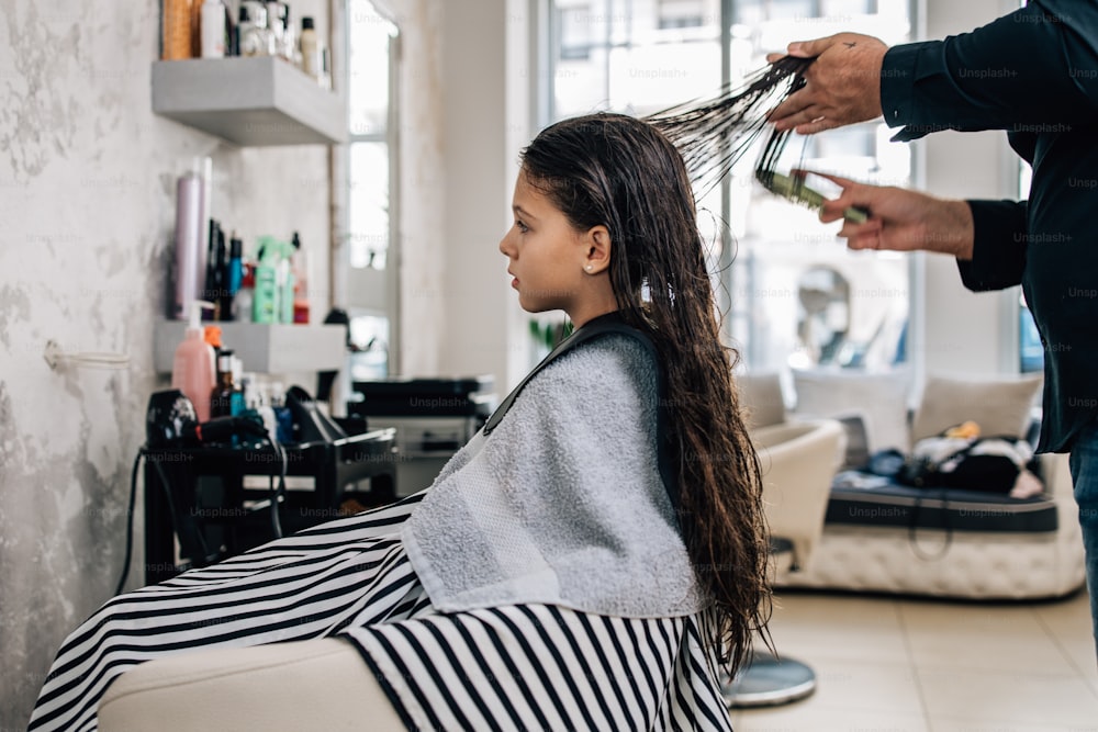 Muchacha joven en el tratamiento del peinado mientras el peluquero profesional se lava suavemente el cabello.