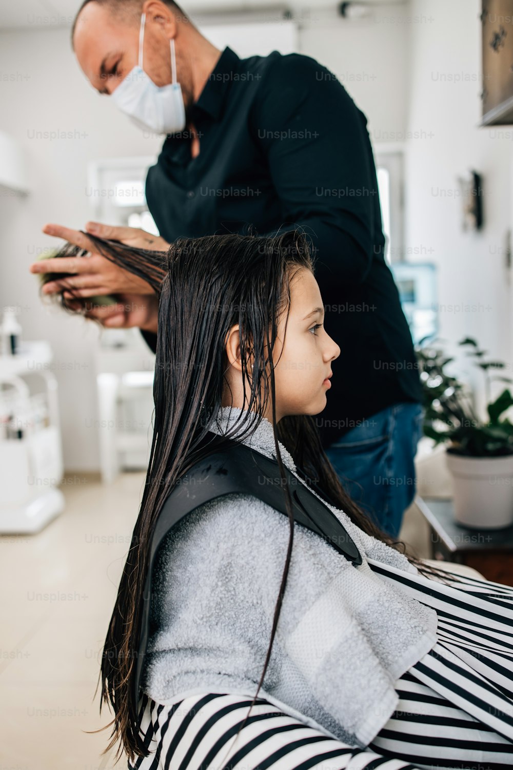 Young girl at hairstyle treatment while professional hairdresser gently washing her hair.