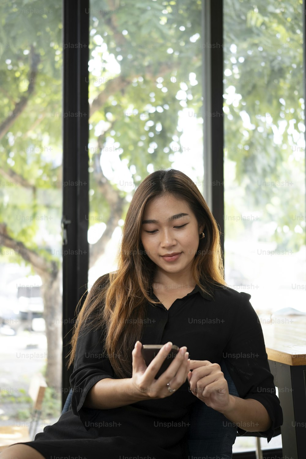Smiling young woman resting at her workplace and using smart phone.