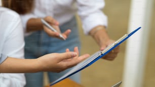 Female manager showing and explain the mistake in financial report to her assistant, hand close up, blurred background