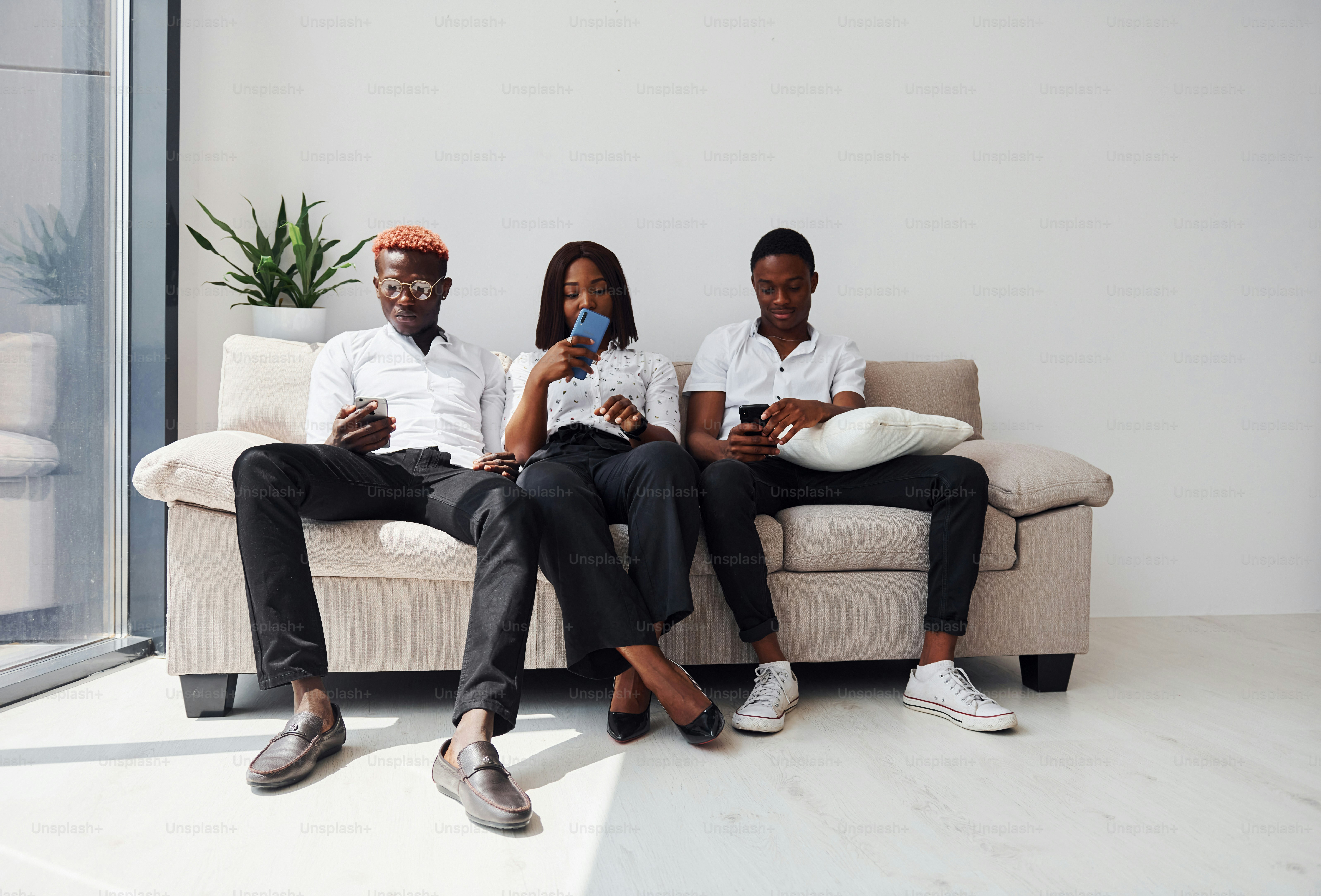 Group of african american people in formal clothes sitting on sofa indoors in office together.