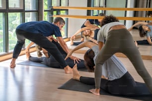 Group of Healthy Asian woman do yoga practicing and body stretching fitness exercise class together with male instructor in yoga studio. Female friends enjoy indoor activity lifestyle and sport training workout.