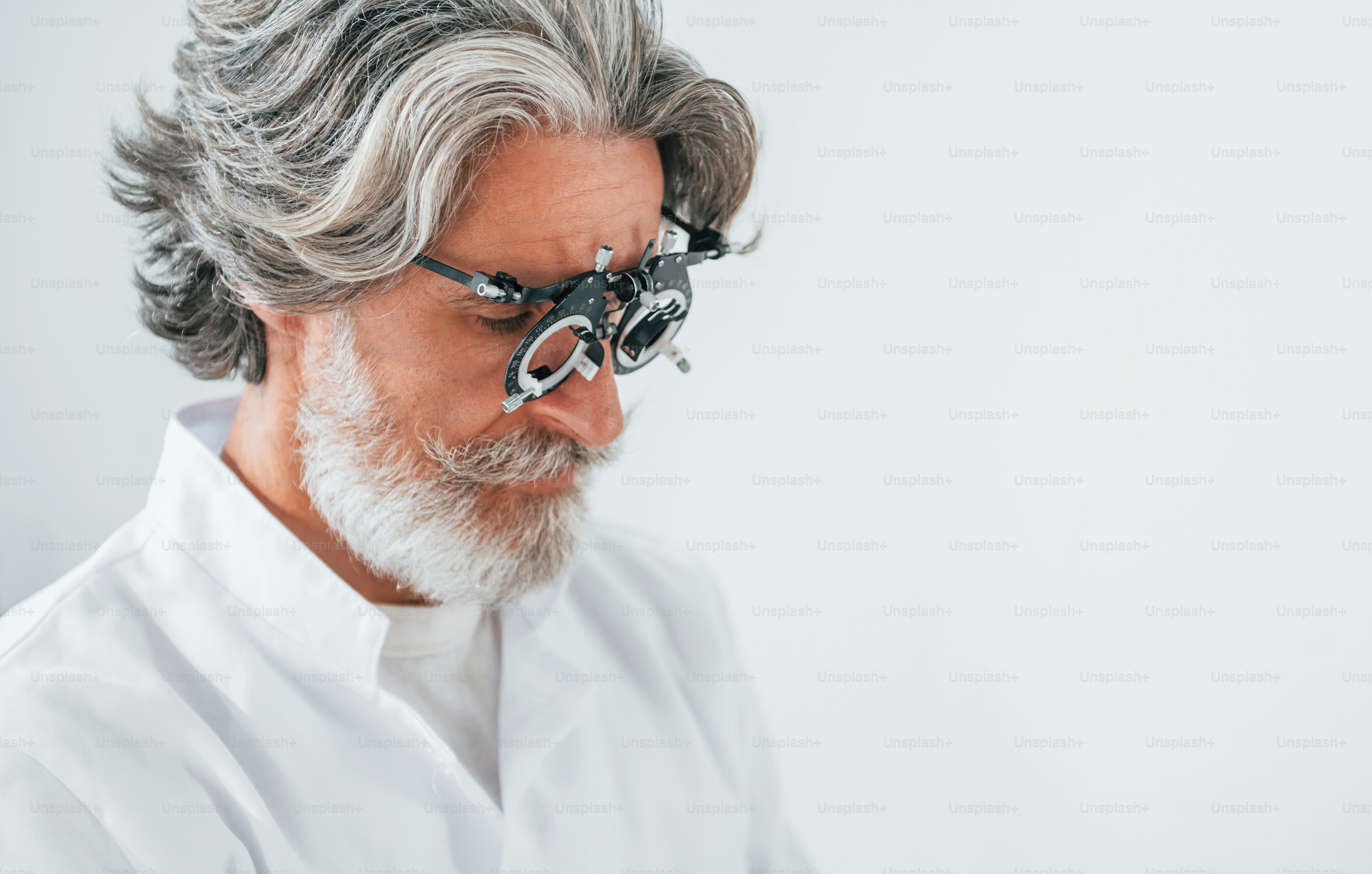 Senior man with grey hair and beard is in ophthalmology clinic.