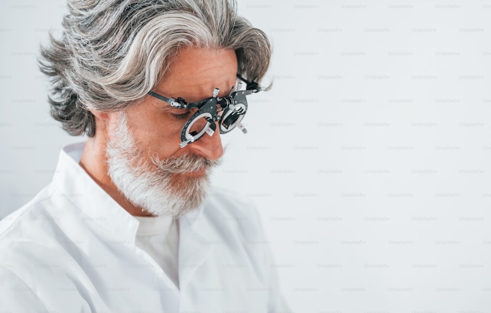 Homem idoso com cabelos grisalhos e barba está na clínica de oftalmologia.