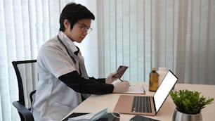 Handsome doctor working with laptop at modern medical office.